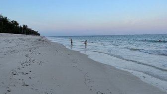 Zwei Kinder spielen am Strand, während sanfte Wellen an den weißen Sandstrand rollen und die Abendstimmung genießen.