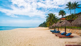 Sandstrand mit Palmen und Liegen lädt zum Entspannen und Spielen für Familien ein – Malaysia & Borneo Reise mit Kindern