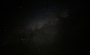 Ein klarer Nachthimmel über Botswana, übersät mit funkelnden Sternen und einem schwachen Nebel im Hintergrund.