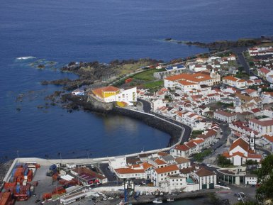 Eine malerische Küstenansicht von Horta auf den Azoren, mit bunten Häusern und einem ruhigen blauen Meer im Hintergrund.