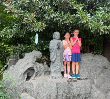 Kinder posieren neben traditionellen Statuen vor der Großen Wildganspagode in Xi’an – China Reise mit Kindern
