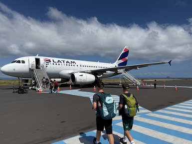 Zwei Kinder mit Rucksäcken gehen zur Treppe eines LATAM-Flugzeugs auf dem Flughafen, um einzusteigen.