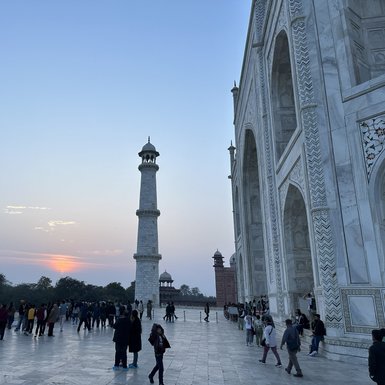 Die majestätische Silhouette des Taj Mahal wird von einem sanften Sonnenuntergang im Hintergrund beleuchtet.