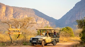 Eine Familie fährt im offenen Jeep durch das Entabeni-Naturreservat – Südafrika Familienreise