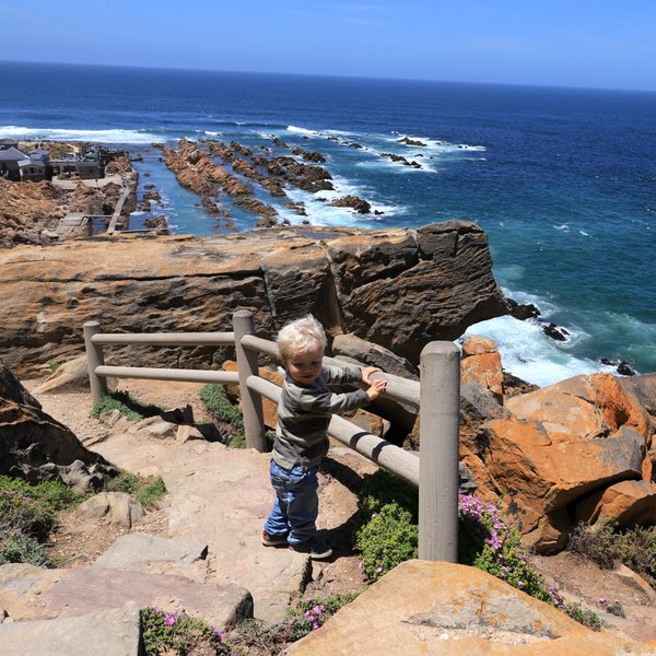Baby schaut von oben auf das Meer in Mossel Bay entlang der Garden Route – Garden Route Familienreise