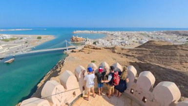 Familie genießt den Ausblick auf die Stadt Sur von einer Terrasse im Oman – Oman mit Kindern