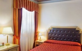 Ein elegantes Hotelzimmer mit einem großen, gepolsterten Bett und einem kunstvoll verzierten Deckenmuster.