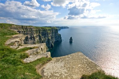 Die beeindruckenden Klippen von Moher erheben sich majestätisch über den ruhigen Atlantik, unter einem strahlend blauen Himmel.