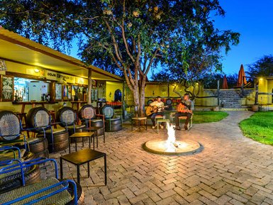 Zwei Musiker spielen Gitarre am Lagerfeuer, umgeben von gemütlichen Sitzgelegenheiten und einer einladenden Atmosphäre.