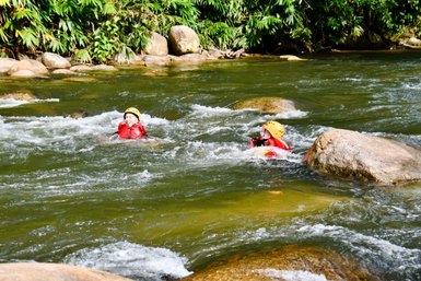 Zwei Kinder schwimmen lachend im klaren Flusswasser nach dem Rafting-Abenteuer – Malaysia & Borneo Familienreise