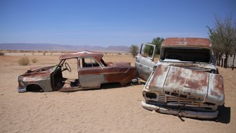 Zwei rostige Autos stehen verlassen in einer Wüste - Namibia mit Kindern