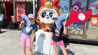 Kinder posieren mit traditionellen Fächern vor einer Pandafigur – China mit Kindern