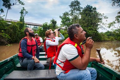 Eine Gruppe von Menschen in roten Schwimmwesten beobachtet die Natur vom Boot aus, umgeben von üppigem Grün und Wasser.