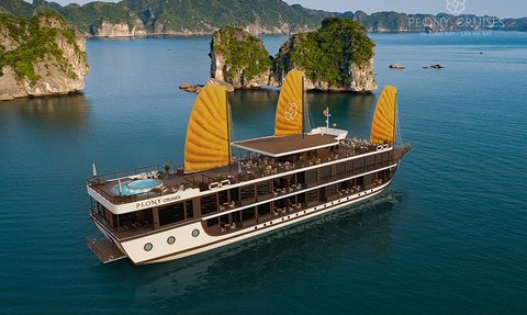 Ein elegantes Kreuzfahrtschiff mit gelben Segeln gleitet über das ruhige Wasser der Lan Ha Bucht, umgeben von grünen Felsen.