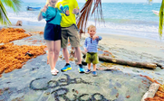 Eine fröhliche Familie posiert am Strand von Costa Rica, während sie mit Daumen hoch und runter für die Kamera zeigt.