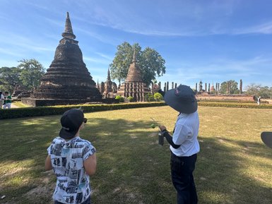 Lokaler Guide führt Touristen durch die Tempelruinen des Wat Mahathat in Sukhothai - Thailand mit Kindern