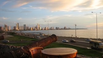 Der Blick auf die Küste von Cartagena zeigt moderne Gebäude, die im Sonnenuntergang golden leuchten, während das Meer sanft plätschert.