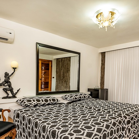 Ein stilvolles Schlafzimmer mit einem großen Bett, das mit einem geometrischen Muster und einem eleganten Spiegel dekoriert ist.