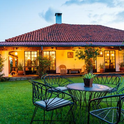 Eine gemütliche Terrasse mit einem Tisch und Stühlen, umgeben von einem gepflegten Garten und einem einladenden Haus.