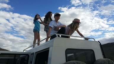 Vier Kinder stehen auf einem Jeep Dach und schauen in die Ferne - Namibia Familienurlaub