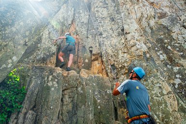 Zwei Personen klettern einen steilen Felsen hoch