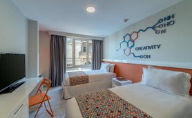 Zwei Einzelbetten mit bunten Bettüberwürfen in einem modernen Hotelzimmer, das Kreativität und Stil ausstrahlt.