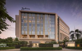 Das moderne Radisson Hotel in Delhi zeigt eine elegante Fassade mit großen Fenstern und einem einladenden Eingangsbereich.