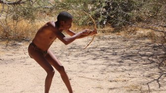 Ein Mann schießt mit einem kleinen Bogen - Namibia mit Kindern