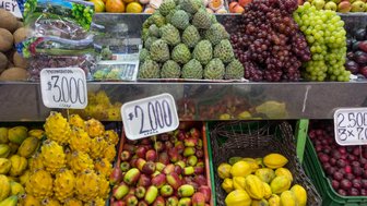 Ein bunter Marktstand mit einer Vielzahl von frischen Früchten, darunter Äpfel, Trauben und exotische Früchte wie Drachenfrucht.