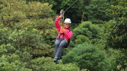 Frau gleitet sicher durch die Baumkronen beim Ziplining – Costa Rica Reise mit Kindern