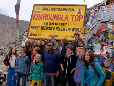 Eine Gruppe von Reisenden posiert vor dem Schild am Khardungla Pass, dem höchsten befahrbaren Weg der Welt.