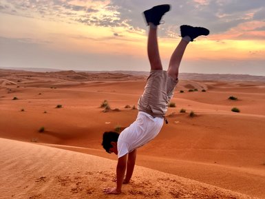 Junge macht Handstand in der Wahiba-Wüste beim Sonnenuntergang – Oman Reise mit Kindern