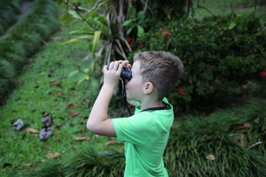 Junge beobachtet die Tierwelt mit Fernglas bei der Maquenque Eco Lodge im Sarapiquí-Tal – Costa Rica Reise mit Kindern