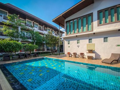 Ein einladender Poolbereich mit glitzerndem Wasser, umgeben von modernen Hotelgebäuden und üppigem Grün.