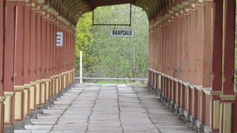 Ein langer, schmaler Gang mit bunten Säulen führt zu einem Schild mit der Aufschrift 'HAAPSALU'.