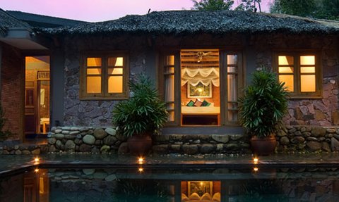 Ein traditionelles vietnamesisches Poolhaus mit einem ruhigen Wasserbecken und sanften Lichtern, umgeben von üppigem Grün.