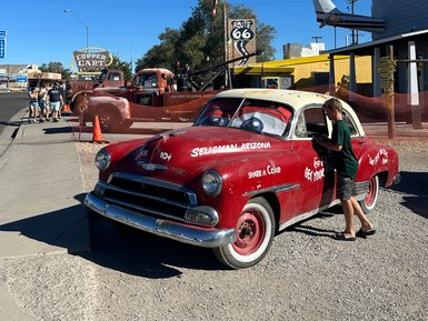 Ein roter Oldtimer steht in Seligman, Arizona, während ein Junge neugierig in das Auto schaut.