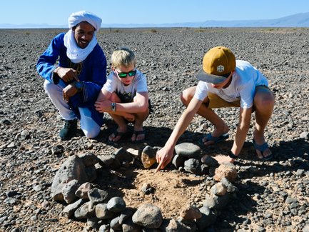Kinder entdecken gemeinsam mit einem Guide interessante Steine – Familienurlaub in Marokko