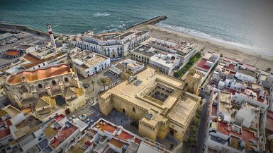 Ein Blick auf die Küstenstadt mit historischen Gebäuden, einem Leuchtturm und dem Meer im Hintergrund.