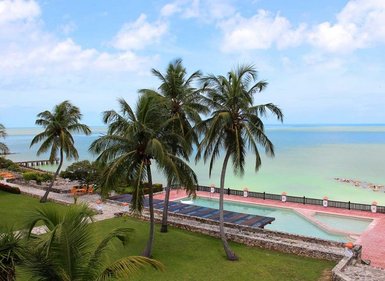Eine malerische Küstenansicht mit Palmen, einem Pool und dem ruhigen, türkisfarbenen Wasser des Karibischen Meeres.