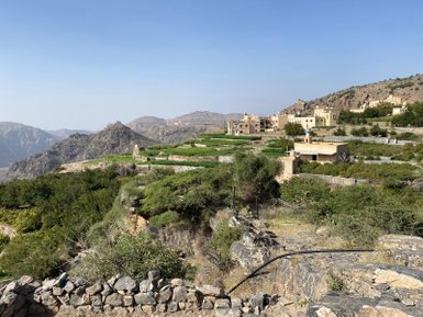 Frau blickt vom Jebel Akhdar auf traditionelle Häuser – Oman Familienreise