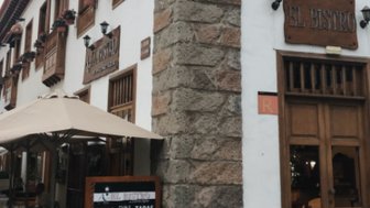 Ein charmantes Restaurant mit dem Namen 'El Bistro', das an einer historischen Steinmauer in einer Stadt liegt.
