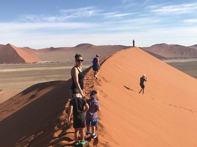 Eine Familie läuft den Kamm einer Sanddüne hinauf - Namibia mit Kindern