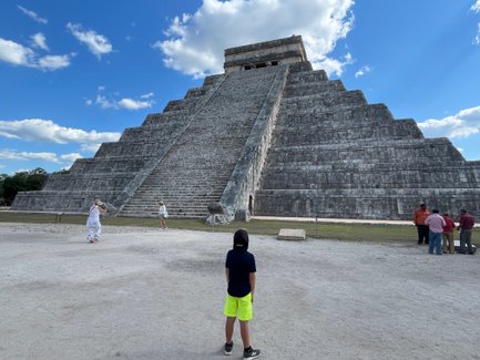 Kind steht vor der Pyramide von Chichén Itzá und blickt nach oben – Mexiko Familienreise