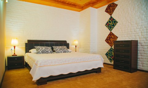 Ein gemütliches Hotelzimmer mit einem großen Bett, dekorativen Kissen und einer stilvollen Lampe neben dem Nachttisch.