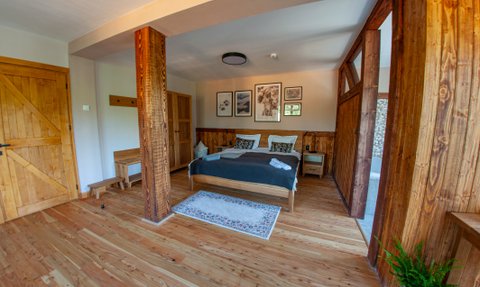 Ein gemütliches Zimmer mit Holzwänden, einem großen Bett und stilvollen Bildern an der Wand, das einladend wirkt.