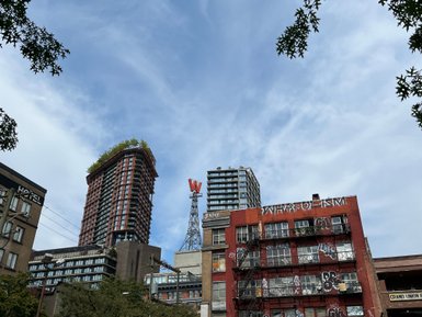 Hochhäuser in Vancouver, darunter ein mit Pflanzen bewachsener Wolkenkratzer und ein graffitibedecktes Gebäude im Vordergrund.