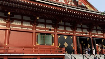 Eine Person steht vor dem beeindruckenden roten Senso-ji Tempel, bewundert die kunstvollen Details und die Architektur.