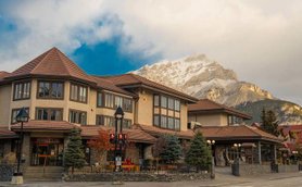 Das Elk Avenue Hotel präsentiert sich mit einer charmanten Fassade und Blick auf majestätische Berge im Hintergrund.