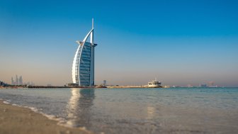 Der Burj Al Arab erhebt sich majestätisch über den sanften Wellen des Strandes in Dubai, unter einem strahlend blauen Himmel.